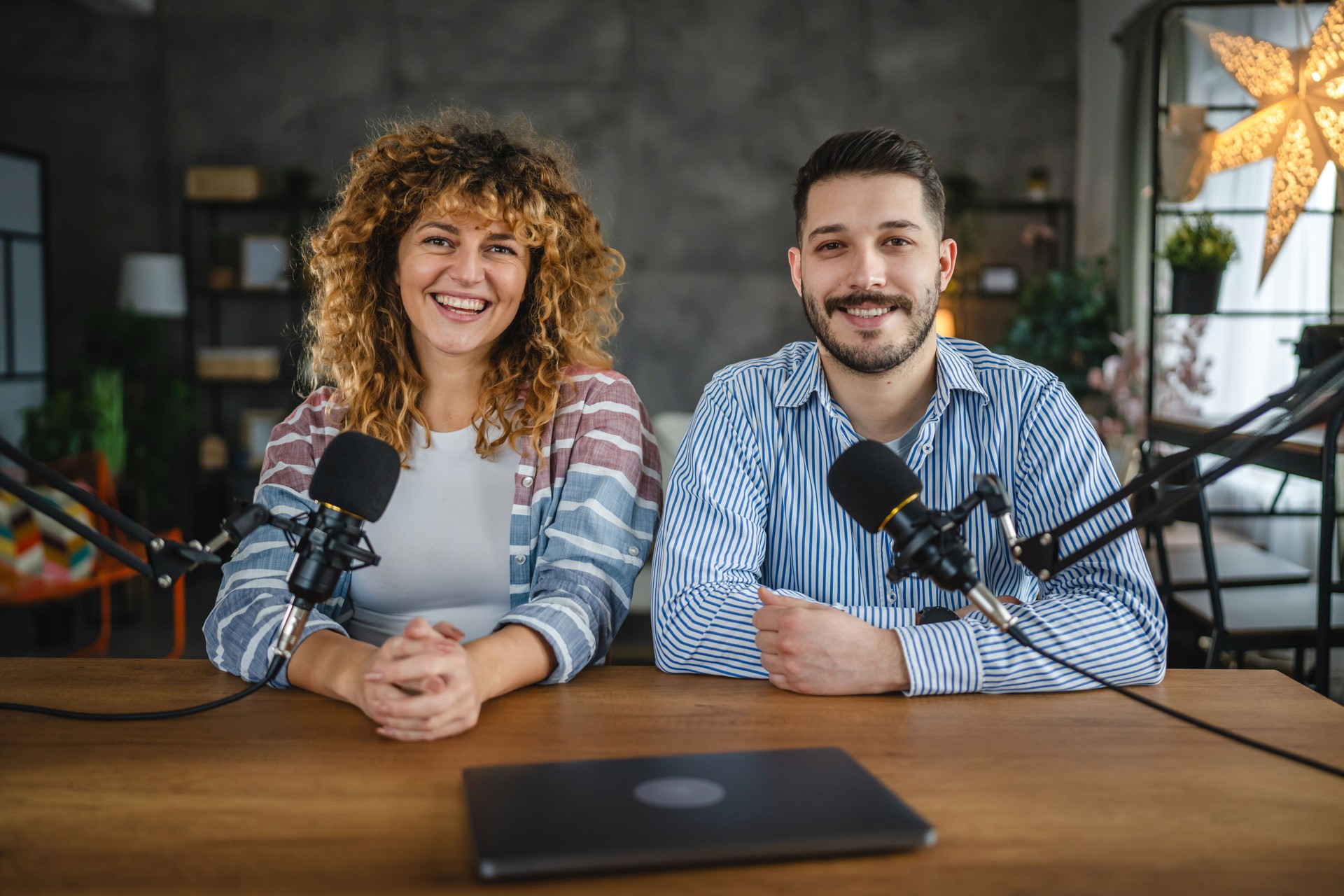 Porträt von zwei Radiomoderatoren, die lachen und genießen, während sie einen Podcast aufnehmen